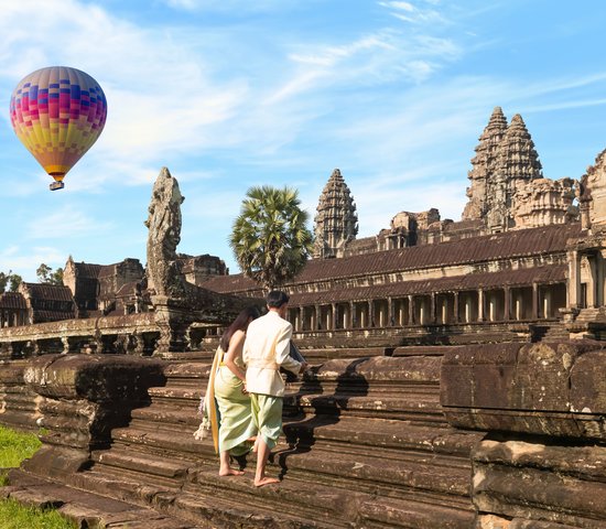 Couple devant le temple Angkor Vat avec vue sur une montgolfière au Cambodge