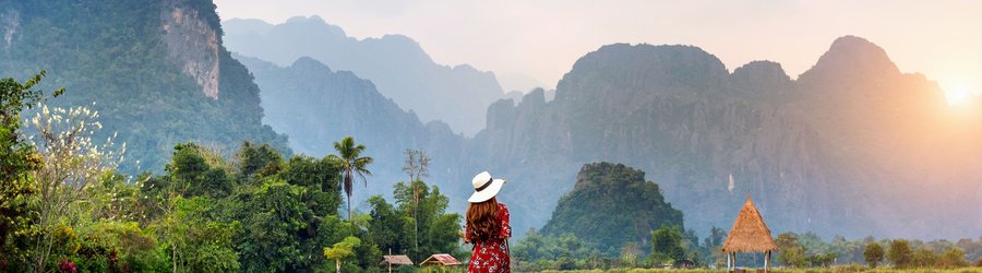 Jeune femme marchant sur un chemin en bois avec un champ de riz vert à Vang Vieng, Laos.