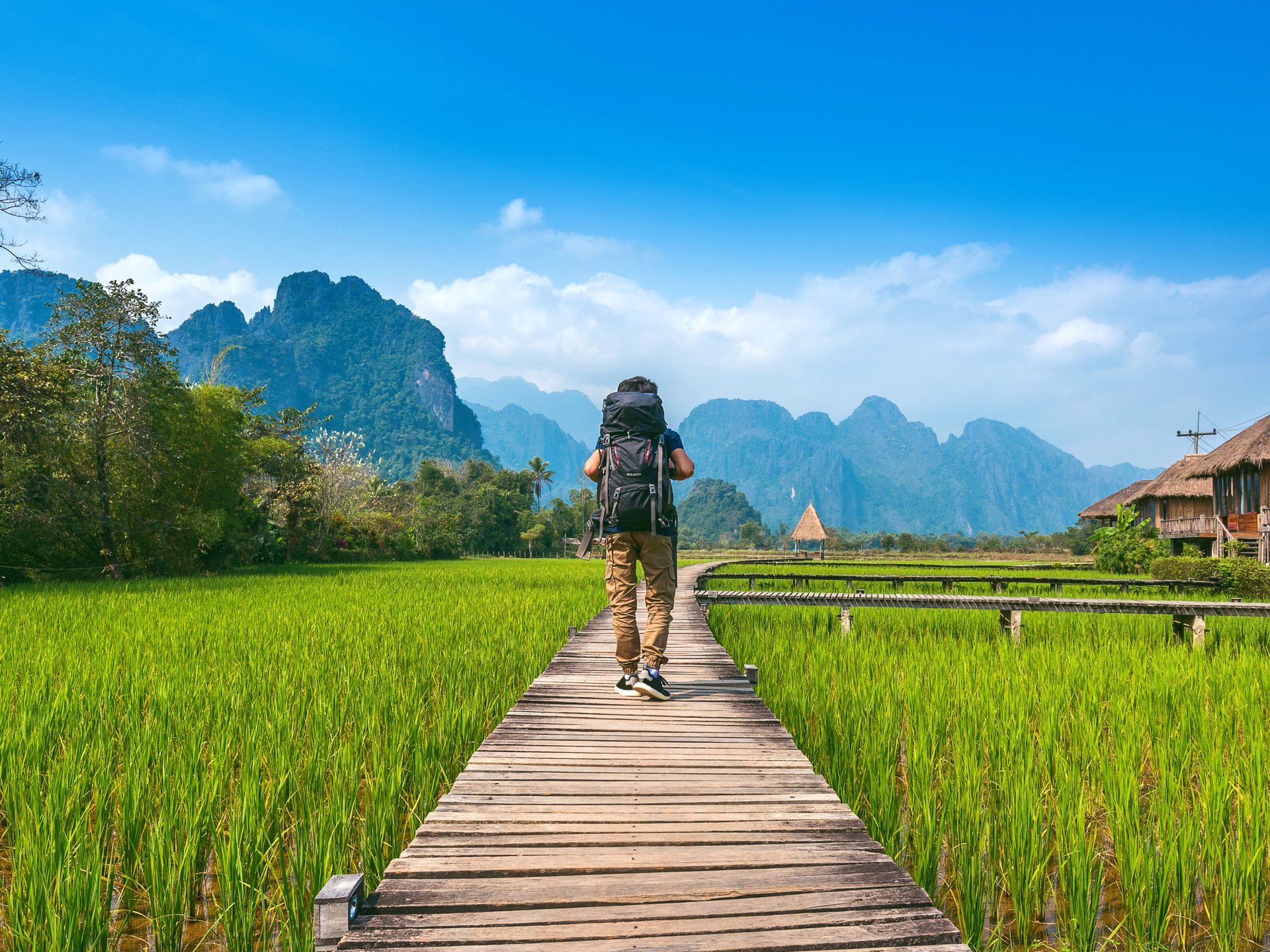 Touriste avec sac à dos marchant sur un chemin en bois, Vang vieng au Laos.