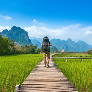 Touriste avec sac à dos marchant sur un chemin en bois, Vang vieng au Laos.