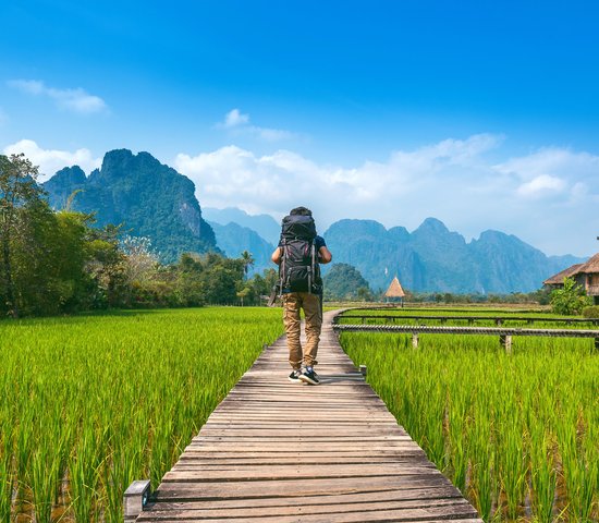 Touriste avec sac à dos marchant sur un chemin en bois, Vang vieng au Laos.