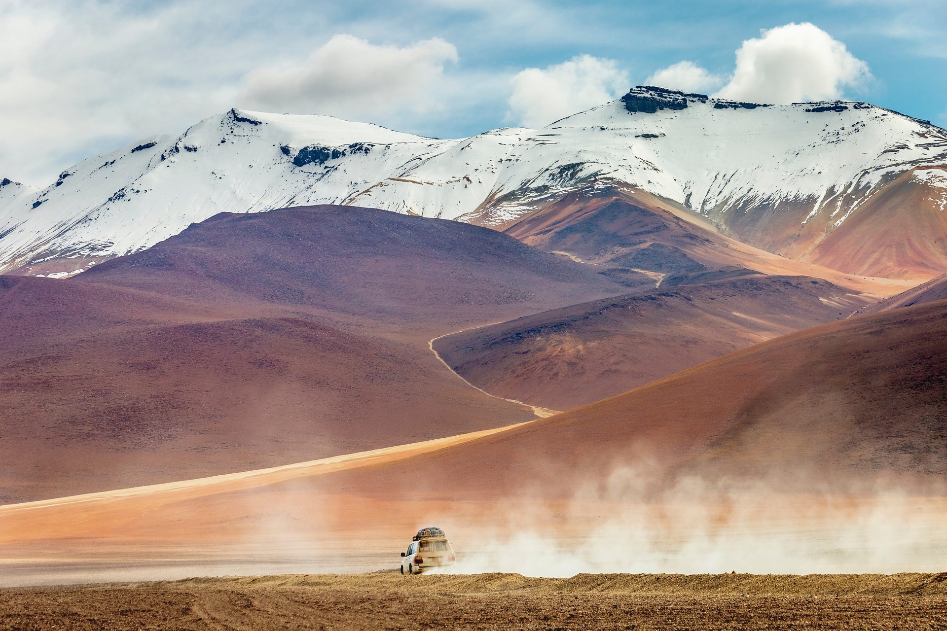 Voiture traversant une route de terre dans le désert d'Atacama, Bolivie