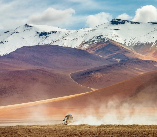 Voiture traversant une route de terre dans le désert d'Atacama, Bolivie