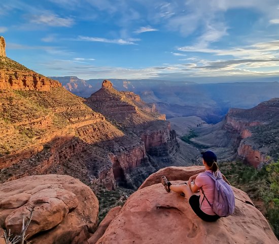 Vue arrière d'une femme avec sac à dos assise sur un rocher le long du sentier Bright Angel avec vue aérienne sur South Rim of Grand Canyon National Park, Arizona, États Unis