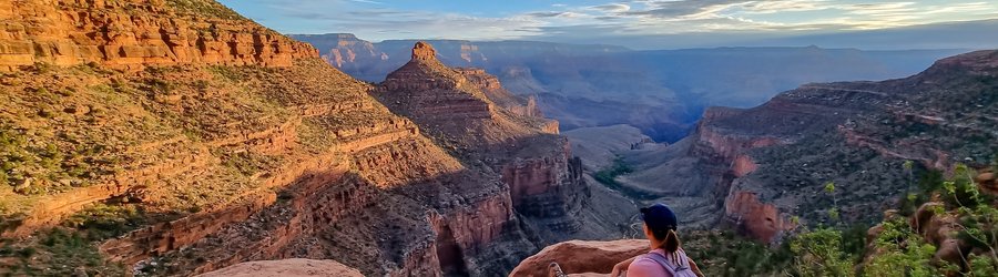 Vue arrière d'une femme avec sac à dos assise sur un rocher le long du sentier Bright Angel avec vue aérienne sur South Rim of Grand Canyon National Park, Arizona, États Unis