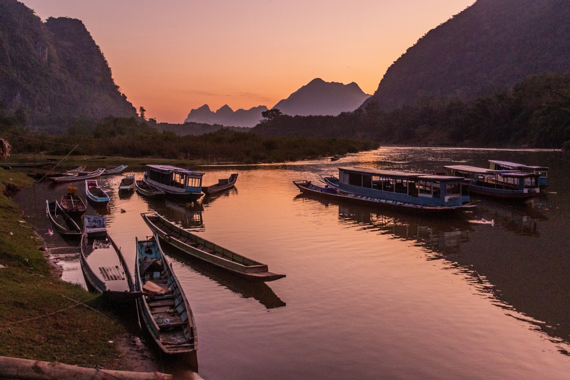 Vue couchée de soleil des bateaux sur la rivière Nam Ou dans le village de Muang Ngoi Neua, Laos