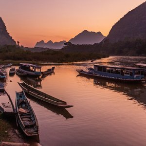 Vue couchée de soleil des bateaux sur la rivière Nam Ou dans le village de Muang Ngoi Neua, Laos