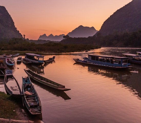 Vue couchée de soleil des bateaux sur la rivière Nam Ou dans le village de Muang Ngoi Neua, Laos