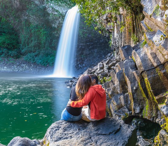 Un couple assis devant la cascade de la paix sur l'île de la Réunion