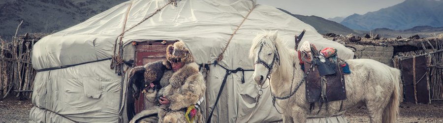 Chasseur d'aigle en tenue traditionnelle devant une yourte en Mongolie